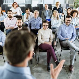 Large group of entrepreneurs listening to public speaker on a seminar in board room.